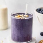 vegan blueberry banana smoothie in a ribbed glass with cashew butter and blueberries
