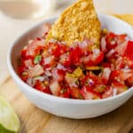 Close-up of chunky fresh tomato salsa with a chip dipping into the bowl