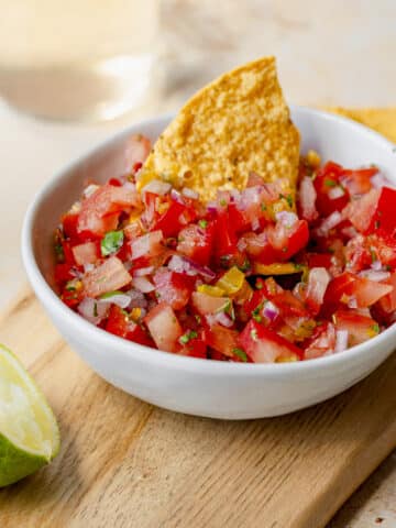 Close-up of chunky fresh tomato salsa with a chip dipping into the bowl