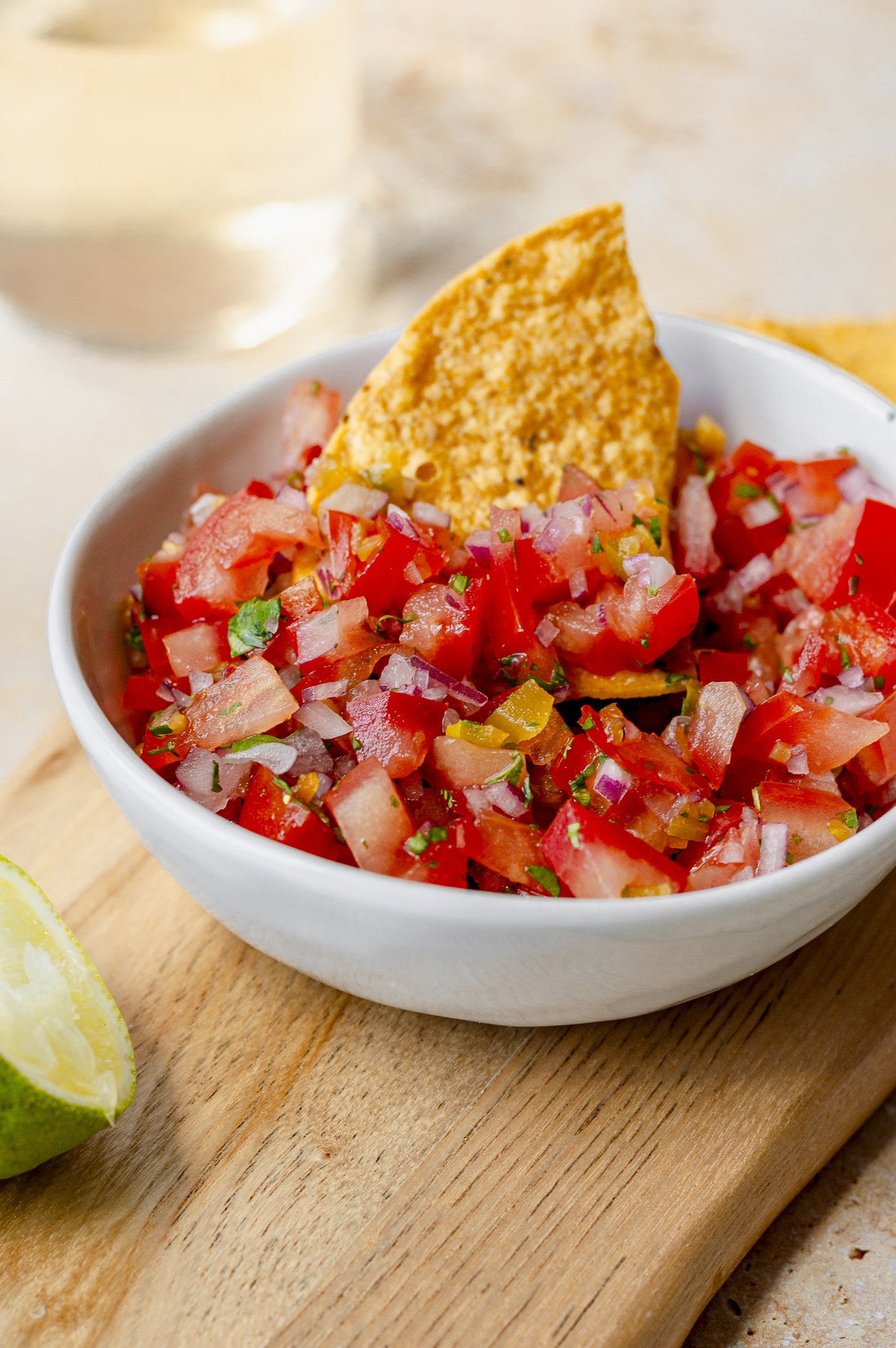 Close-up of chunky fresh tomato salsa with a chip dipping into the bowl