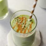 a peanut butter green protein smoothie in a glass with a brown and white straw