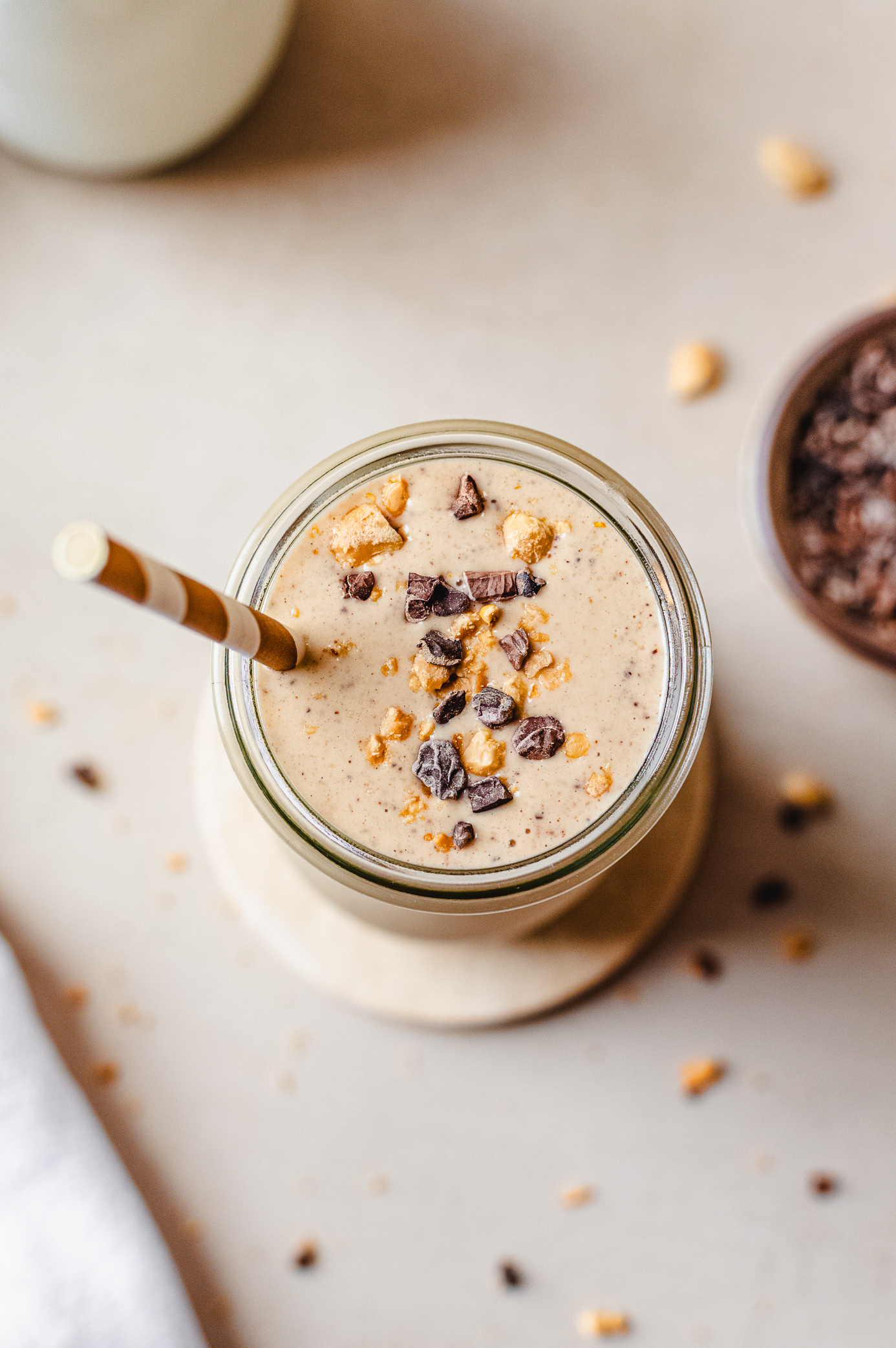 Overhead view of a chunky monkey smoothie topped with crushed cacao nibs and peanuts
