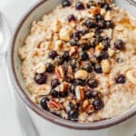 Creamy peanut butter oatmeal topped with blueberries, cinnamon, chopped peanuts and pecans