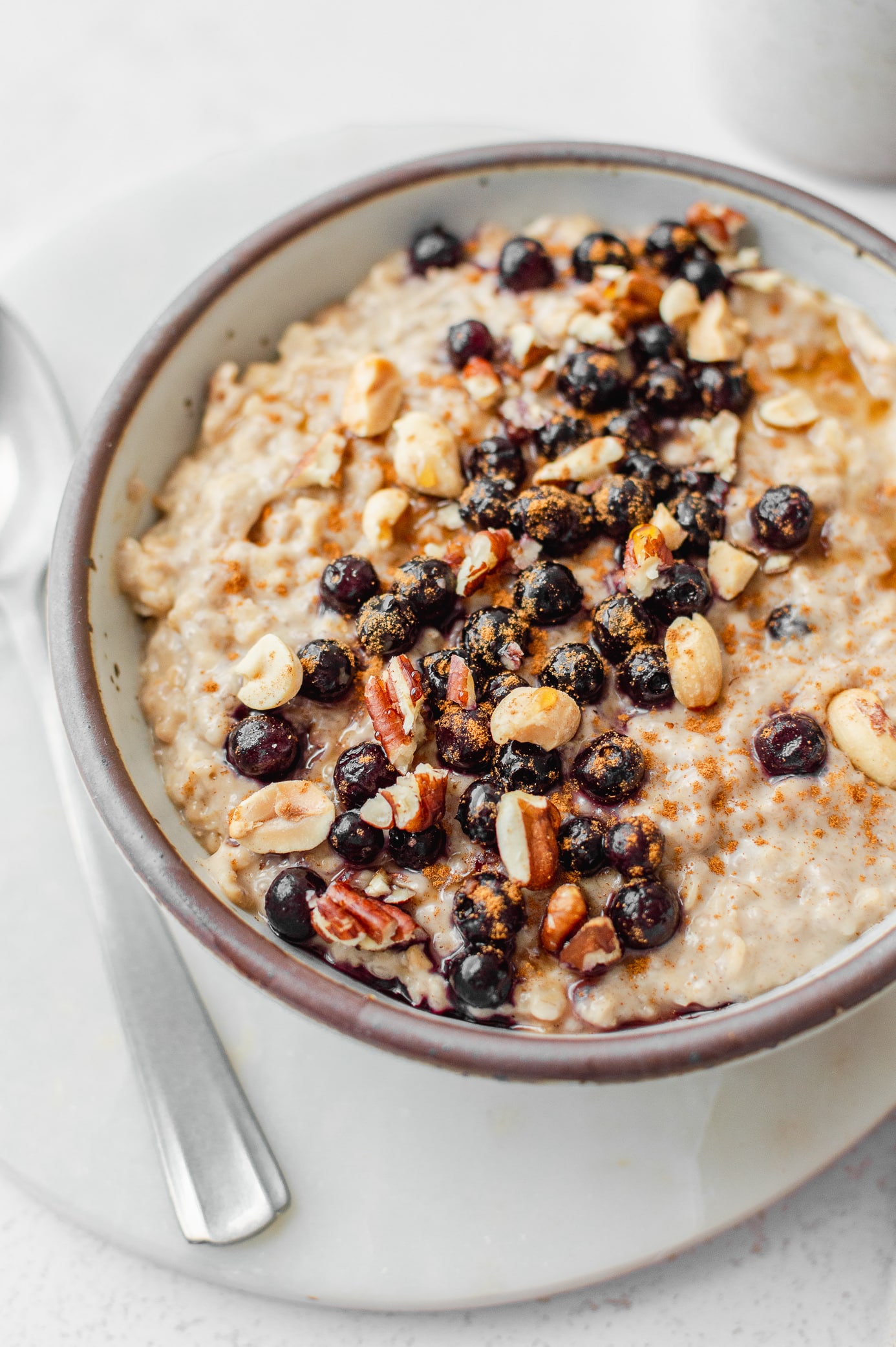 Creamy peanut butter oatmeal topped with blueberries, cinnamon, chopped peanuts and pecans
