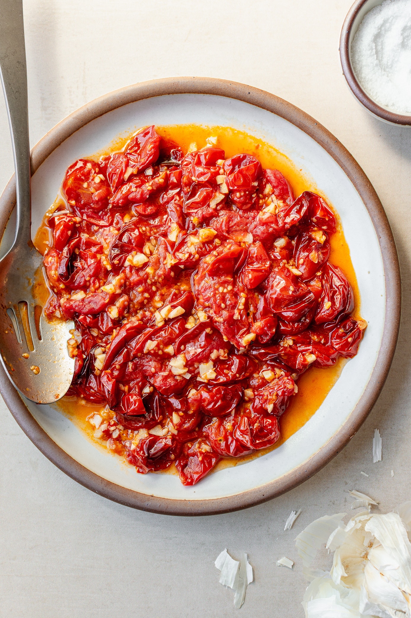 oven roasted cherry tomatoes with garlic on a plate in a rich, jammy garlicky oil