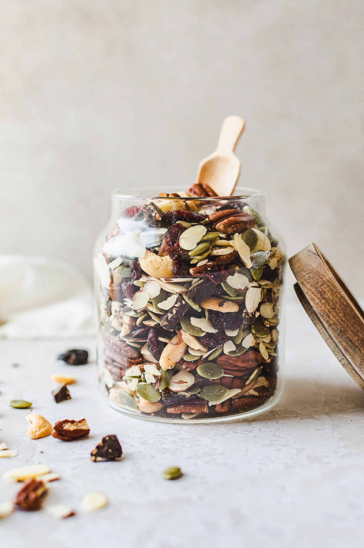 Glass jar filled with homemade vegan trail mix with a wooden scoop