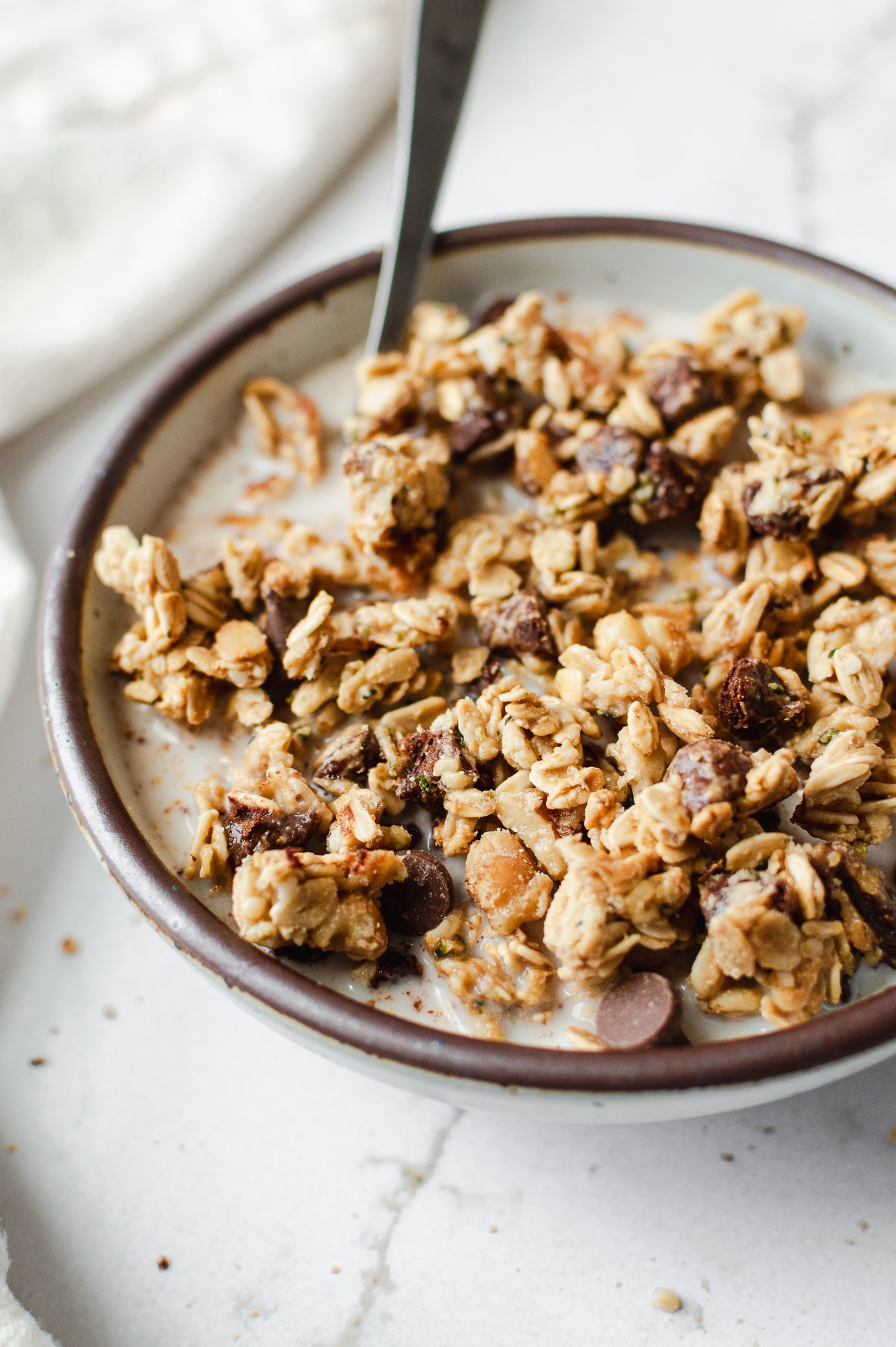 Close-up of chunky chocolate chip cookie dough granola clusters in a bowl with milk.