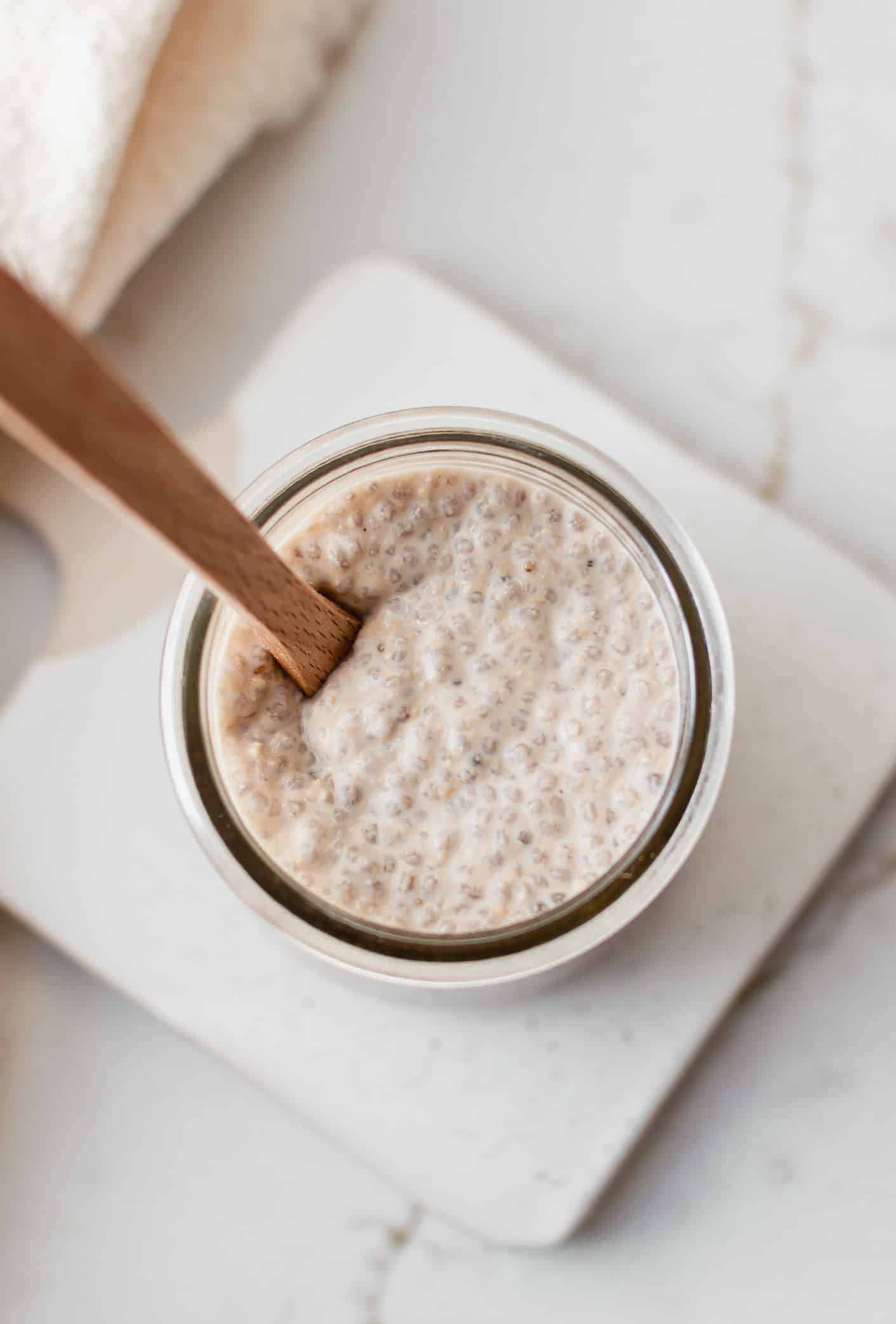 Overhead view of cookie dough chia pudding in a jar with a wooden spoon