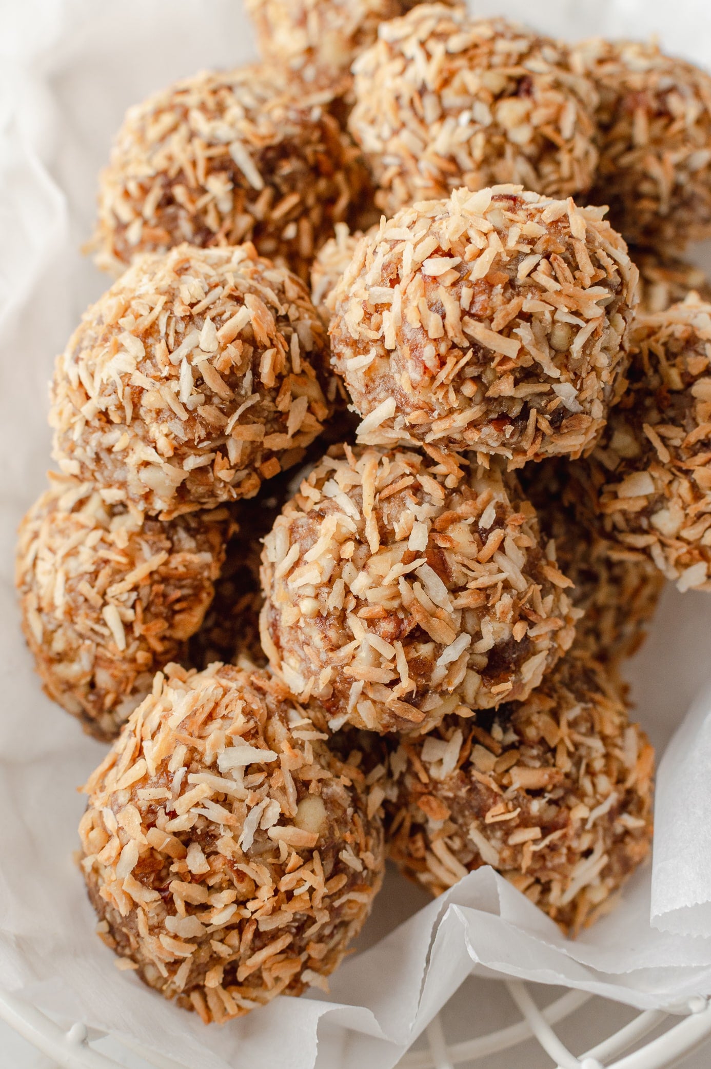 cinnamon coconut date bites in a basket with white parchment paper