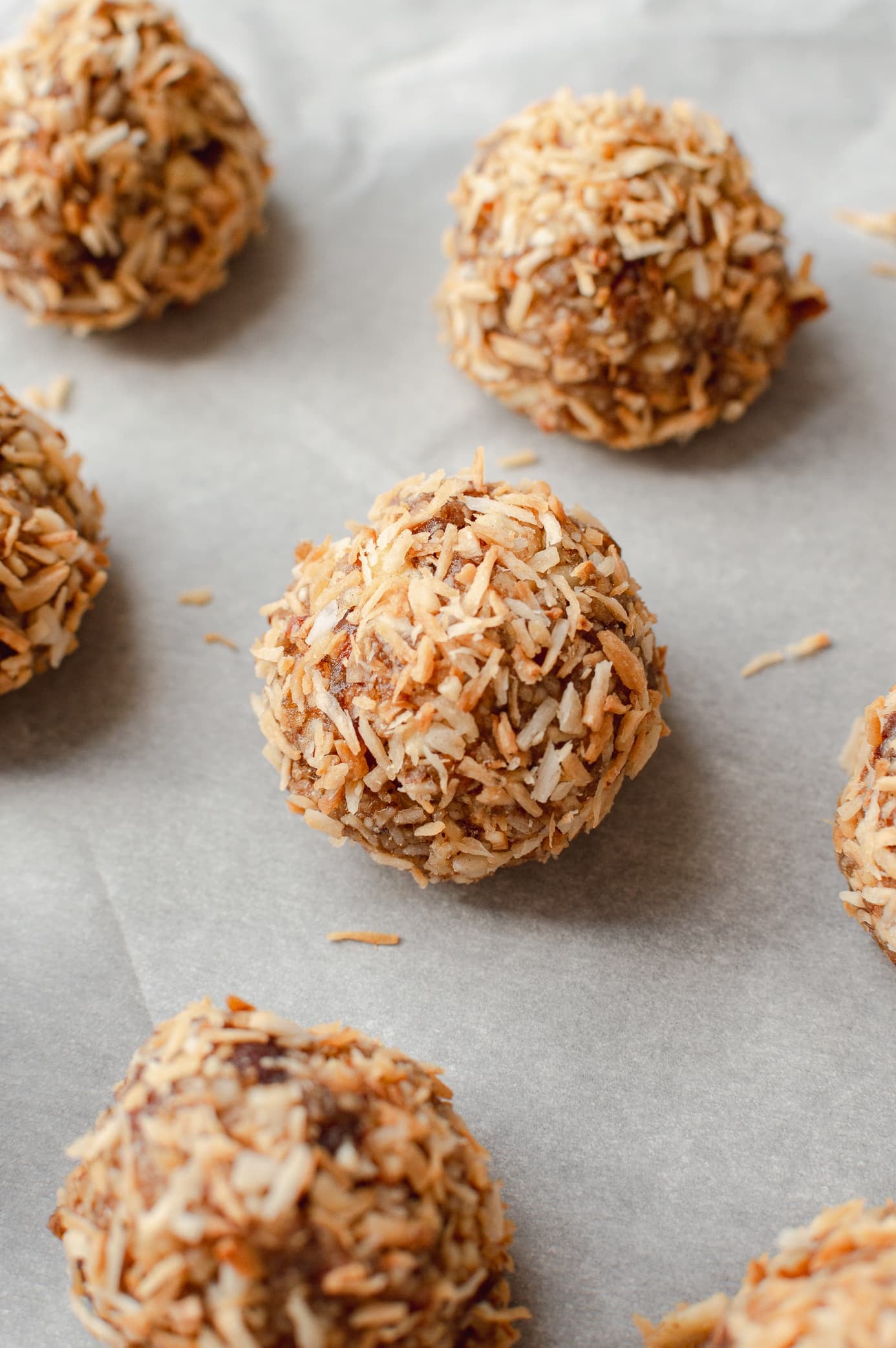 nut and date bites rolled in toasted coconut on a baking sheet