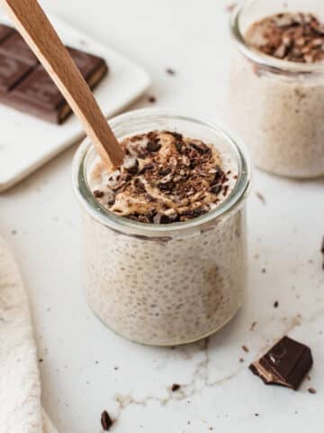 Cookie dough chia pudding in a glass jar topped with chopped dark chocolate and cashew butter