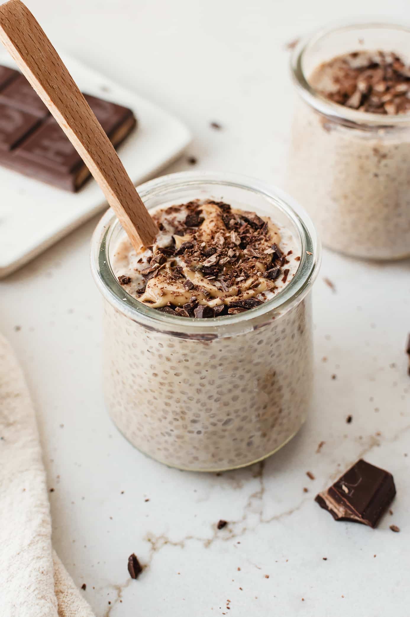 Cookie dough chia pudding in a glass jar topped with chopped dark chocolate and cashew butter