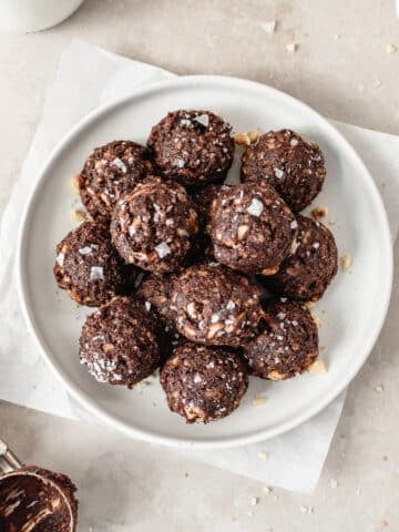 date brownie bites topped with flaky sea salt on a white plate