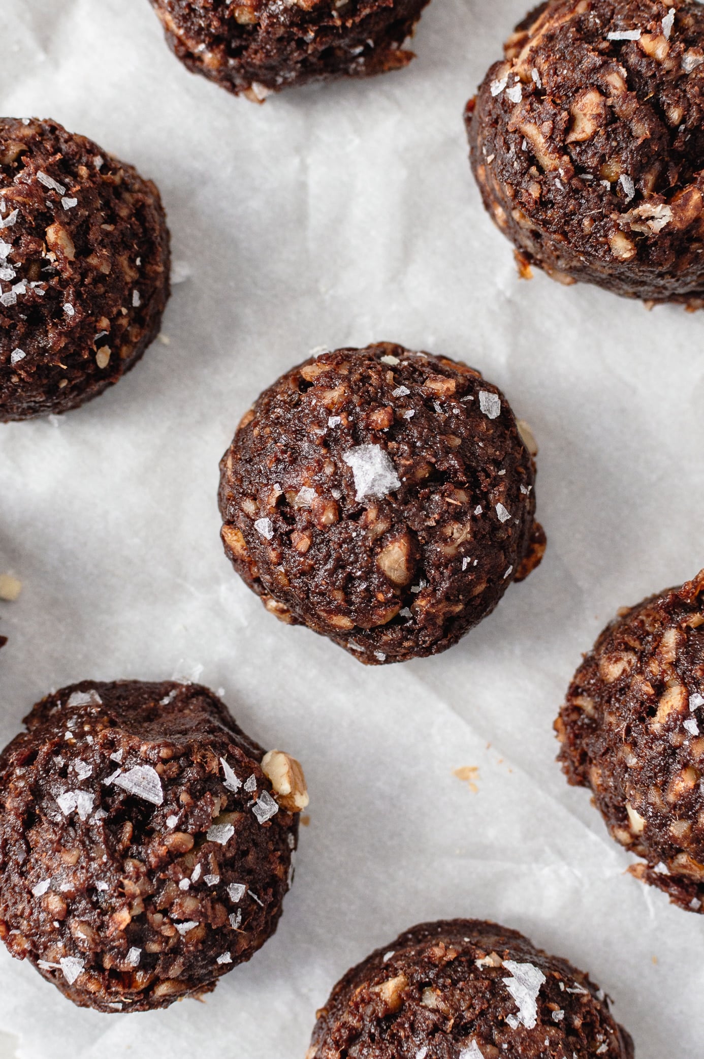 date brownie bites topped with flaky sea salt on parchment paper